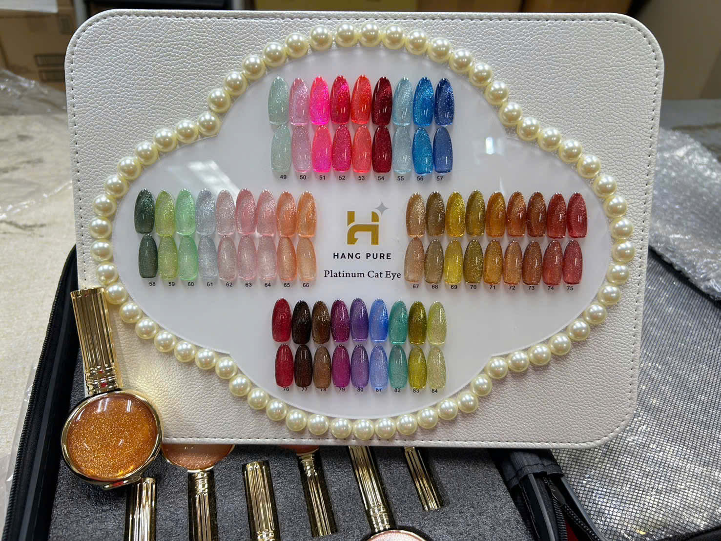 Set of false nails with a color chart and application tools on a white case.